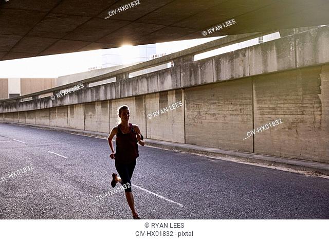 Female runner running into urban tunnel