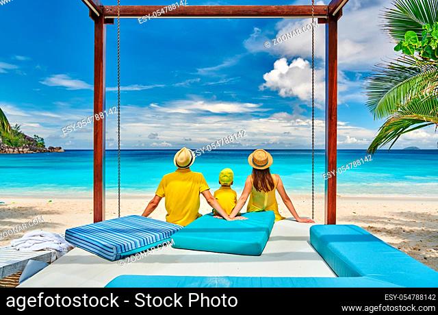 Family on beautiful Petite Anse beach, young couple in yellow with three year old toddler boy. Summer vacation at Seychelles, Mahe