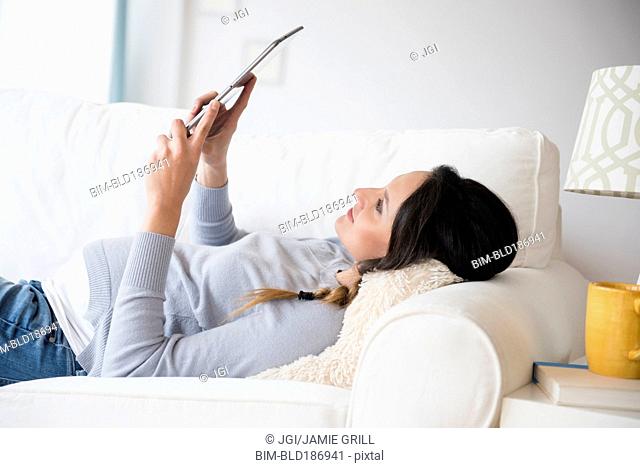 Pregnant Caucasian woman using digital tablet on sofa