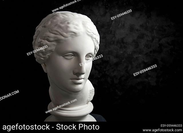White gypsum copy of ancient statue of Venus de Milo head for artists on a dark textured background. Plaster sculpture of woman face