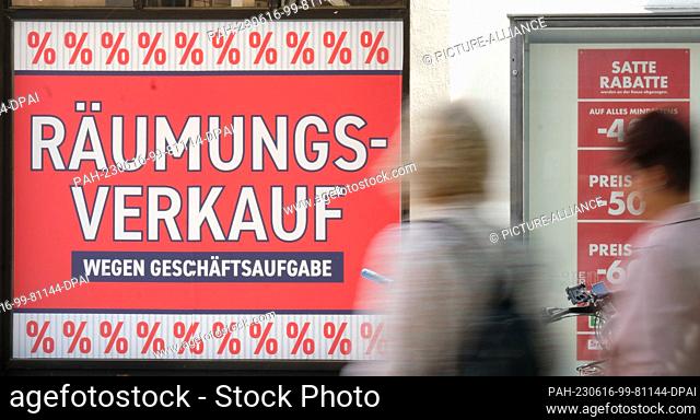 16 June 2023, Baden-Württemberg, Stuttgart: Two women walk past a retail clothing store in downtown Stuttgart with a banner that reads ""Clearance sale due to...