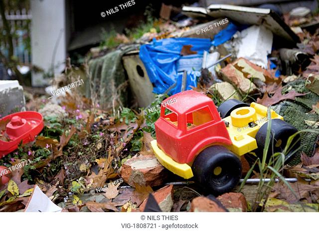 GERMANY, BREMERHAVEN, 09.11.2009, Old plastic toy car in the garbage on the courtyard of an occupied house - Bremerhaven, Bremen, Germany, 09/11/2009