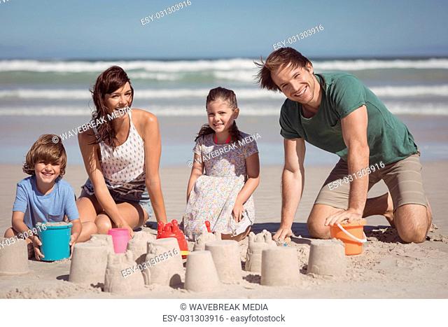 Portrait of happy family making sand castle at beach