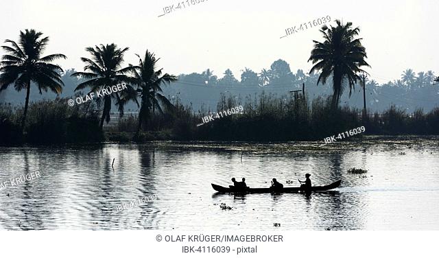 Woman taking children to school in a small boat, Backwaters canal system, Kerala, South India, India