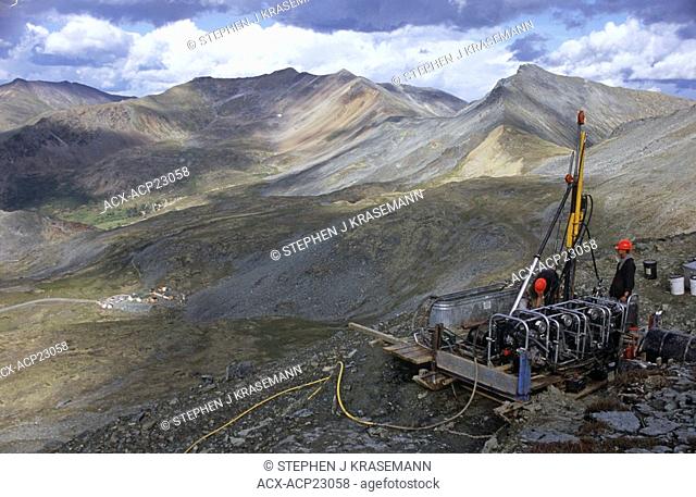 Drilling operators drilling for mineral core samples, Pelly Mountains, Yukon Territory, Canada