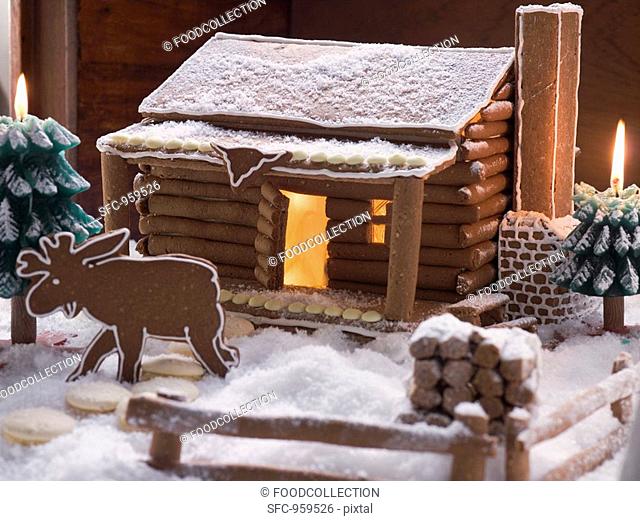 Gingerbread log cabin in snowy forest with gingerbread elk