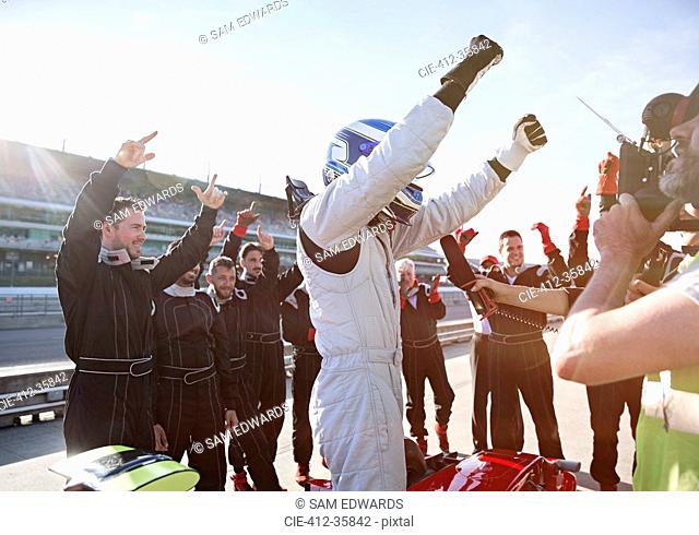 Formula one racing team and driver cheering, celebrating victory on sports track