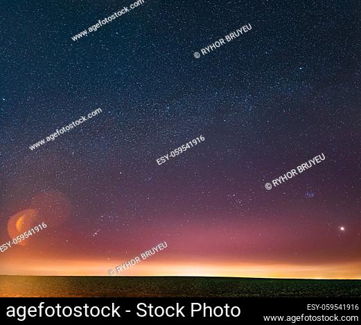 Night Starry Sky With Glowing Stars Above Countryside Landscape. Milky Way Galaxy And Rural Field Meadow In Early Spring