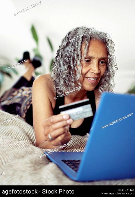 Senior woman with credit card online shopping at laptop