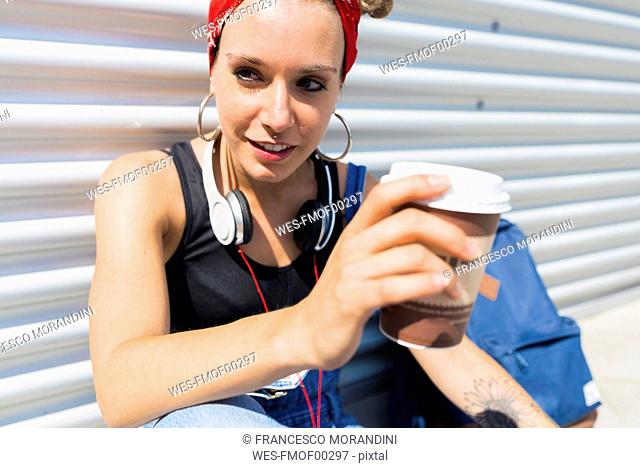 Portrait of young woman with headphones and coffee to go