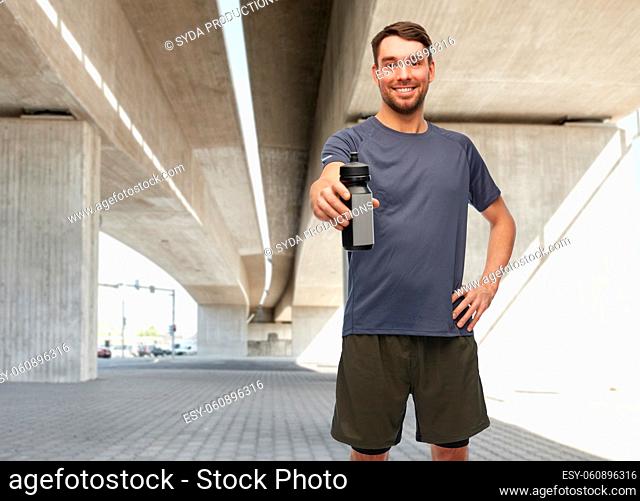 smiling man in sports clothes with bottle