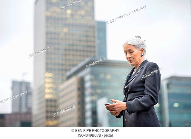 Businesswoman using mobile phone, Canary Wharf, London, UK