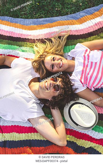 Happy young couple lying on blanket in park