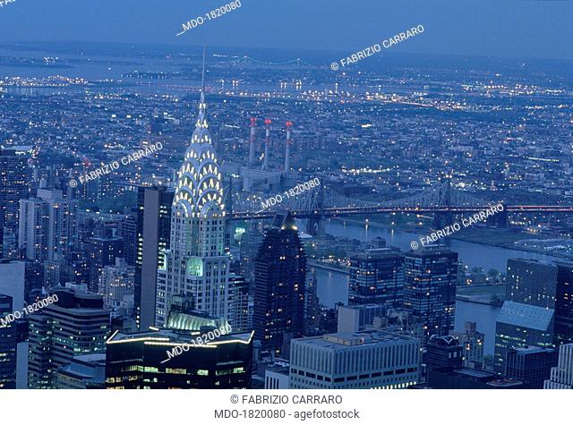 View of Manhattan island by night; on the left, completely illuminated, the Chrysler Building; finished in 1930, the building is one of the highest skyscrapers...