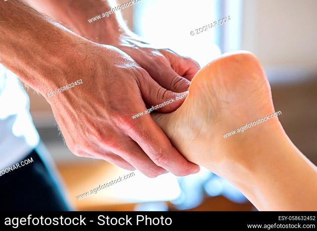 Close-up of a young woman receiving leg massage in a cosy home environment. Massage therapist massaging legs of female. Massage and body care