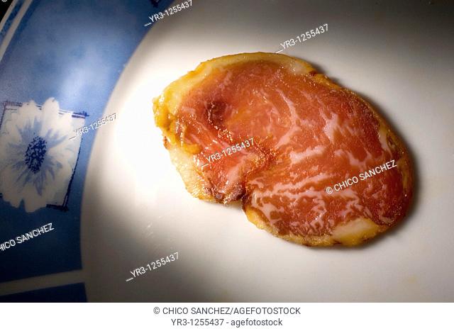 A cured loin slice made from Spanish Iberian pigs, the source of Iberico ham known as pata negra, sits on a plate in Prado del Rey, Sierra de Cadiz