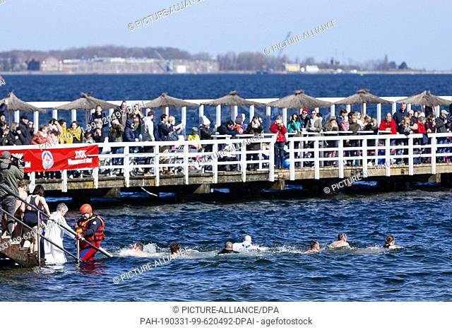 31 March 2019, Schleswig-Holstein, Kiel: Visitors to an open-air swimming pool jump into the seven-degree cold Kiel Fjord while ""bathing"" together