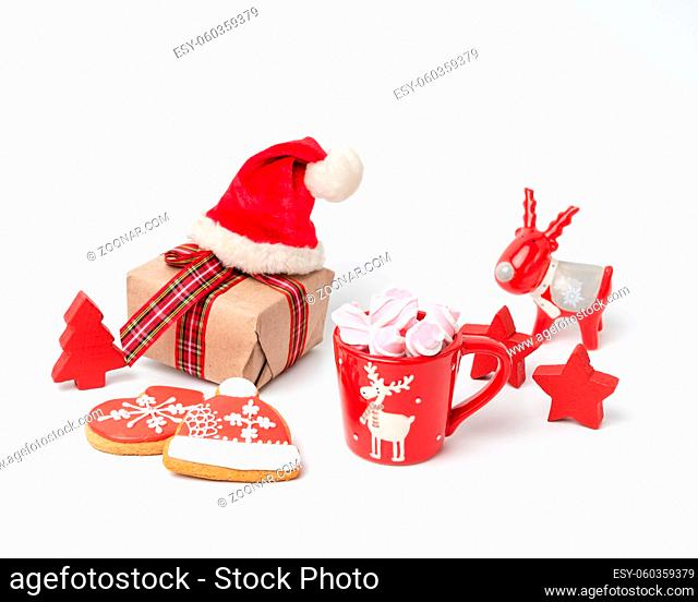 red ceramic cup with drink and marshmallows, near baked christmas gingerbread, white background