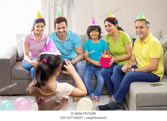 Little girl taking photo of family on birthday party