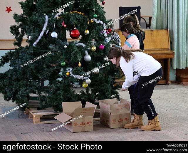 RUSSIA, ZAPOROZHYE REGION - DECEMBER 18, 2023: Kids decorate a Christmas tree at school No 4 in the town of Pologi. The school has 440 students who come from...