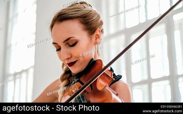 Young Attractive Woman In A Beautiful Dress Is Playing The Violin. The Violinist Is Full Of Inspiration And Excitement