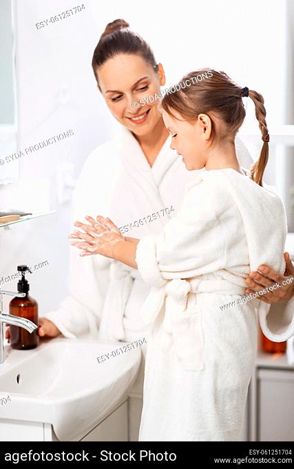 mother and daughter with liquid soap in bathroom