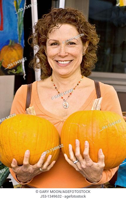 Woman holding two pumpkins at farmers' market, Nevada City, California