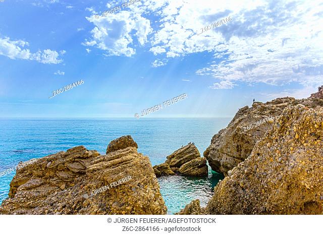 rocks at the coast, waves reflecting sunbeams in clear water, Mediterranean Sea of the Costa del Sol, Andalusia, Spain
