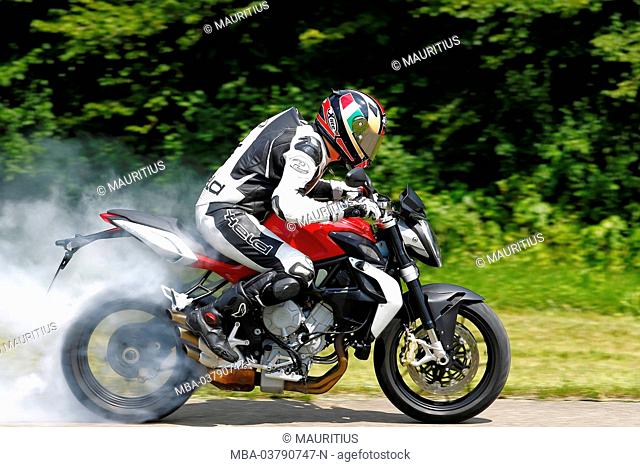 Motorcycle, three-cylinder engine, MV Agusta Brutale 675 tripistoni, year of construction in 2012, Burnout on country road, panned, smoking rear tire