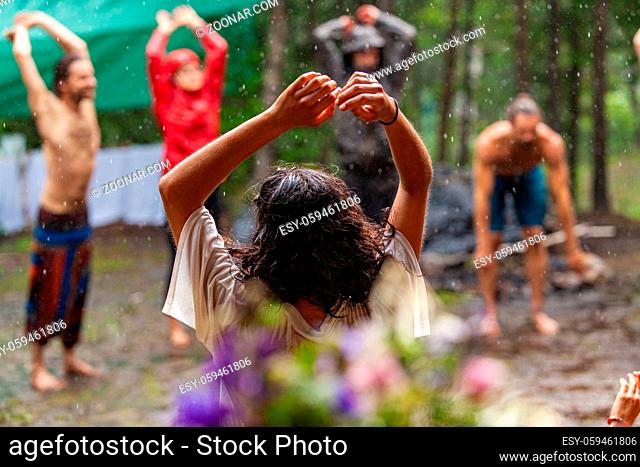 A multigenerational group of people are seen standing in a circle in a forest clearing, worshipping native cultures during a mindful congregation in nature