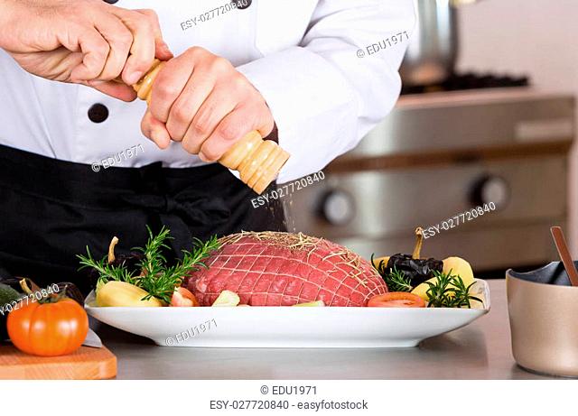 Chef putting pepper in a round of beef