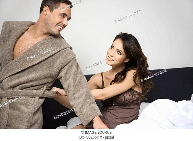 A woman pulling at a mans bathrobe