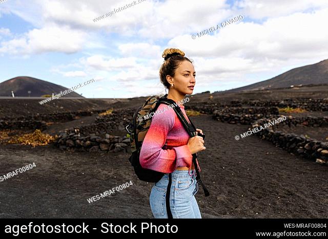 Woman with backpack hiking on dirt road