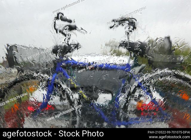 22 May 2021, Schleswig-Holstein, Niebüll: Through a windscreen with raindrops a bicycle on the rear rack of a car can be seen during the crossing with the...