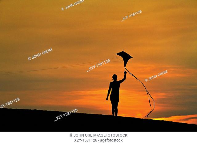 Silhouette of a child flying a kite