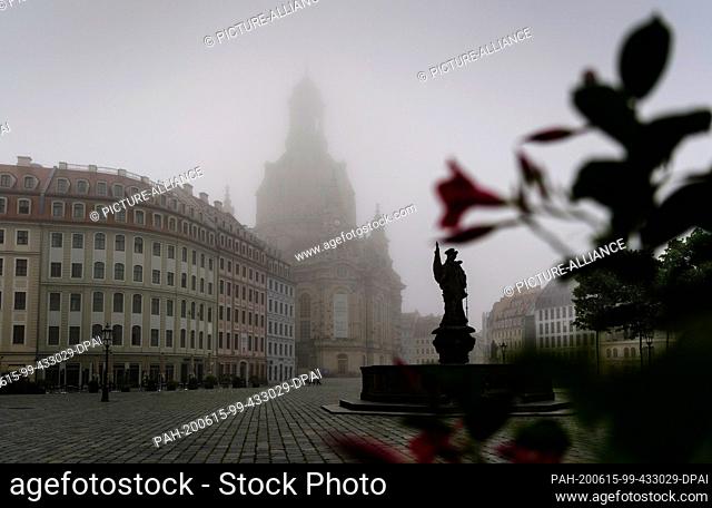 15 June 2020, Saxony, Dresden: The Neumarkt in front of the Frauenkirche and the Friedensbrunnen are shrouded in fog in the morning