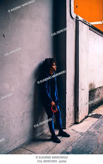 Young man waiting in front of concrete wall