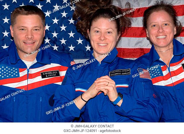 NASA astronauts Doug Wheelock, Tracy Caldwell Dyson (center) and Shannon Walker, all Expedition 24 flight engineers, pose for a photo with an American flag...