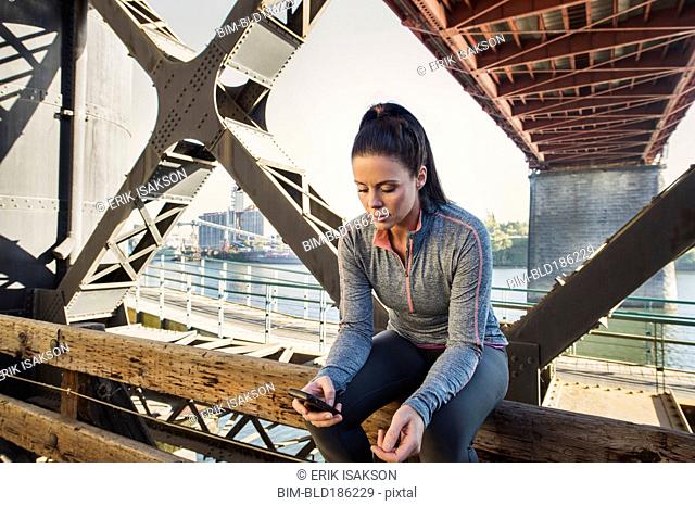 Caucasian woman sitting on urban bridge