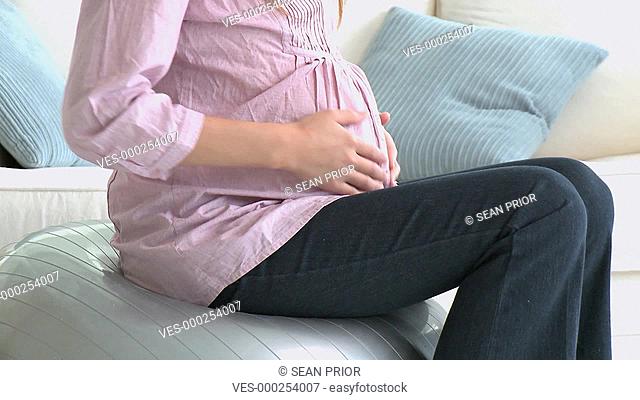 Eine schwangere Frau streichelt ?ber ihren Babybauch