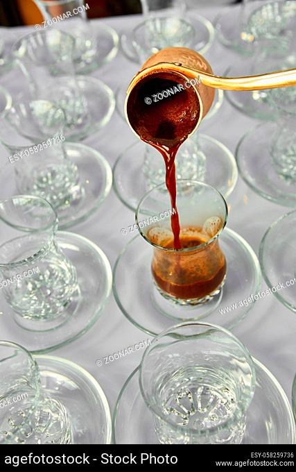 Pouring turkish coffee into traditional embossed glass cup