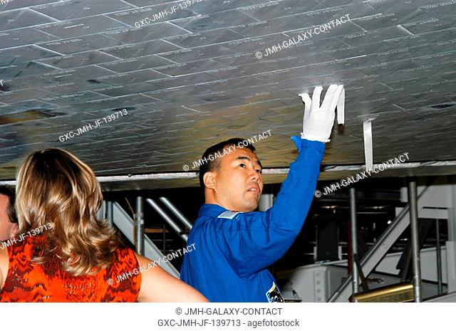 Astronaut Soichi Noguchi, STS-114 mission specialist representing Japan Aerospace Exploration Agency (JAXA), takes a close look at tiles underneath the Space...