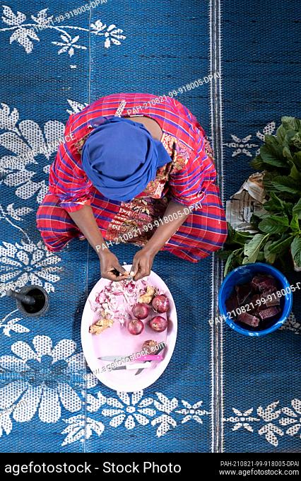 03 August 2021, Tanzania, Sansibar: A woman sits on the floor peeling garlic. Photo: Sebastian Kahnert/dpa-Zentralbild/dpa