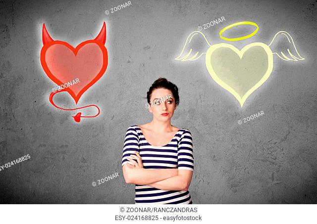 Woman standing between the angel and devil hearts