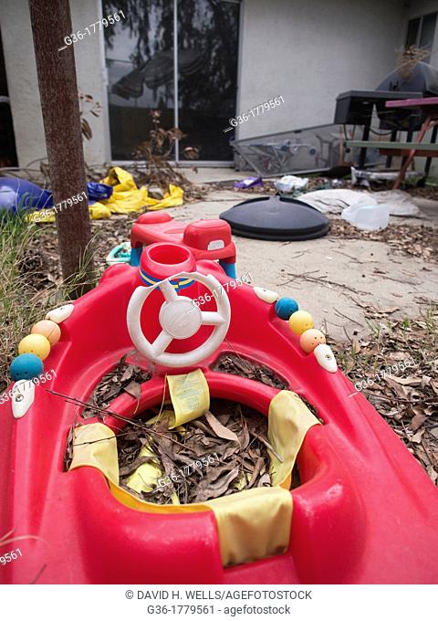 Red childs toy in messy yard inside of a foreclosed home in Fresno, California, United States