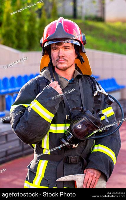 Portrait of heroic fireman with an axe outdoors
