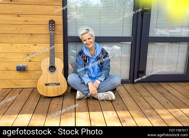 Portrait happy woman sitting with guitar on patio