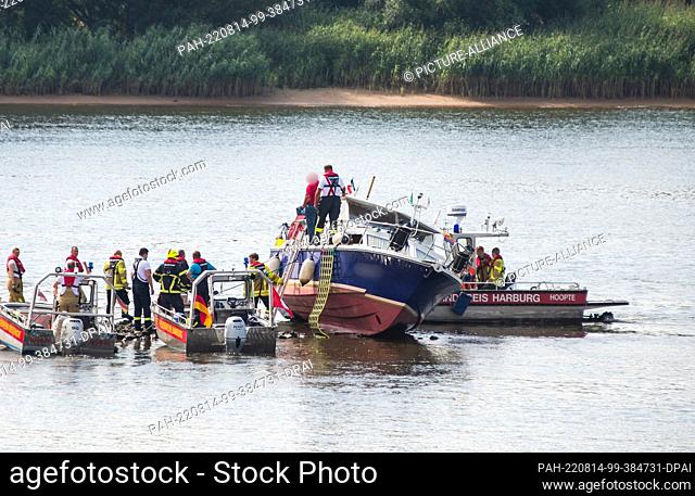14 August 2022, Hamburg: Emergency personnel with boats work on a pleasure boat on the Elbe near Altengamme. The boat, manned by three people