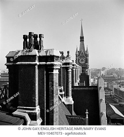 Numbered chimney pots on the roof of the station buildings at St Pancras Station with the clock tower visible in the distance