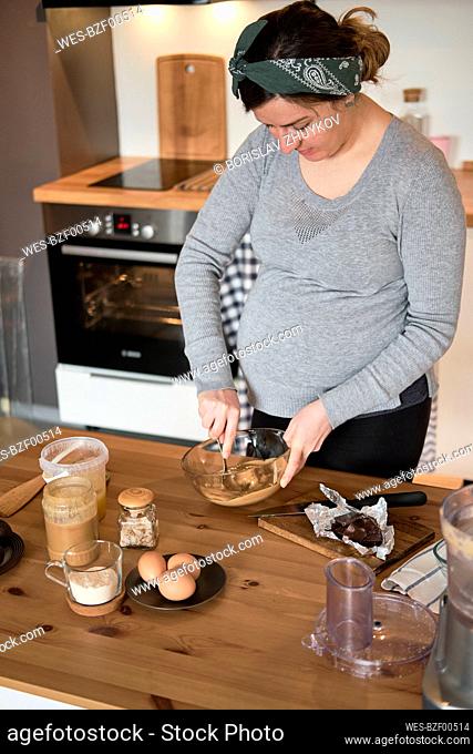 Pregnant woman making healthy cake with tahini, walnuts and dark chocolate at home